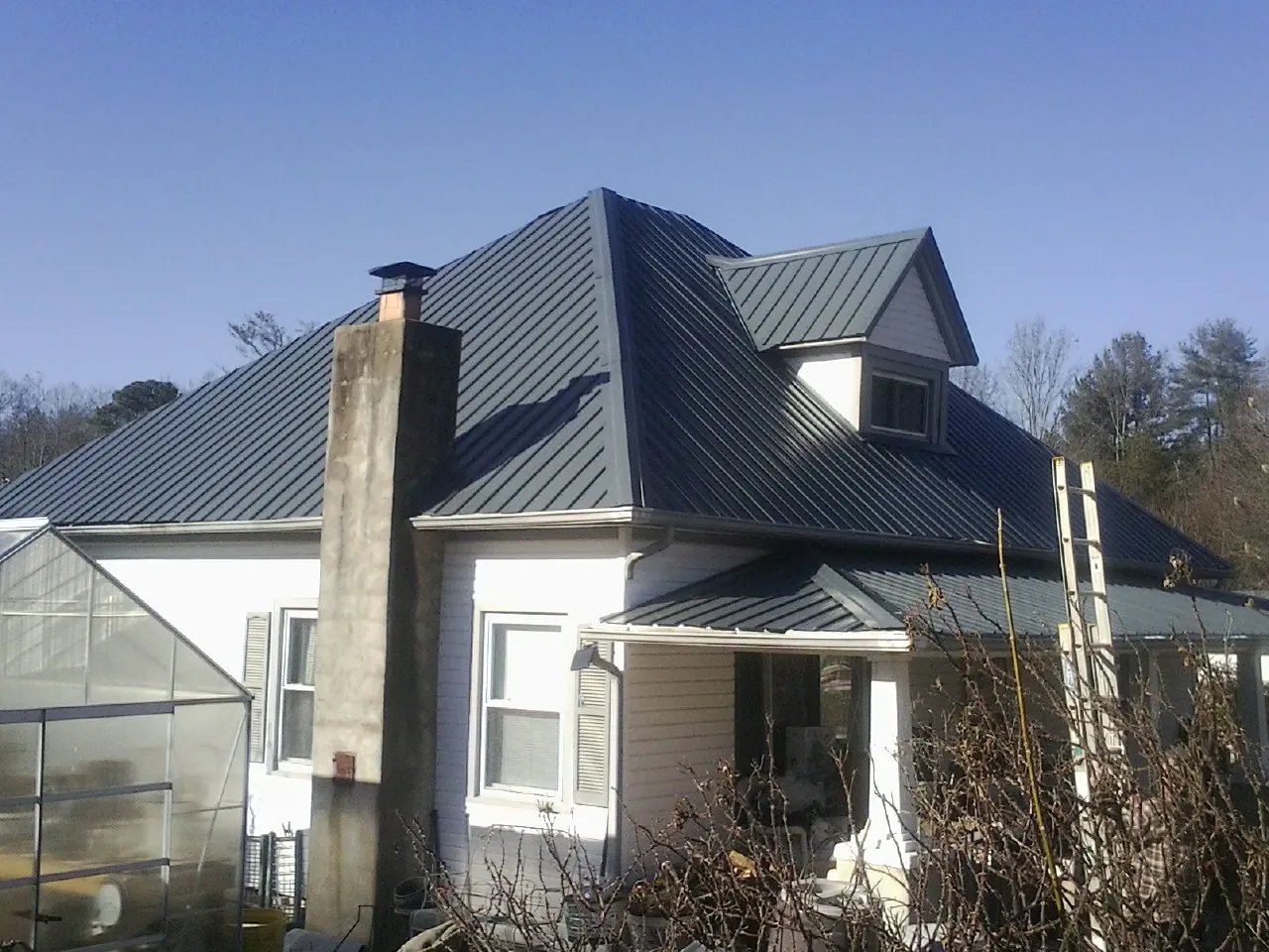 Dark blue standing seam metal roof on a white farmhouse with dormer — Slate & Tile Roof Repair by Roofing Brothers in Eden Valley