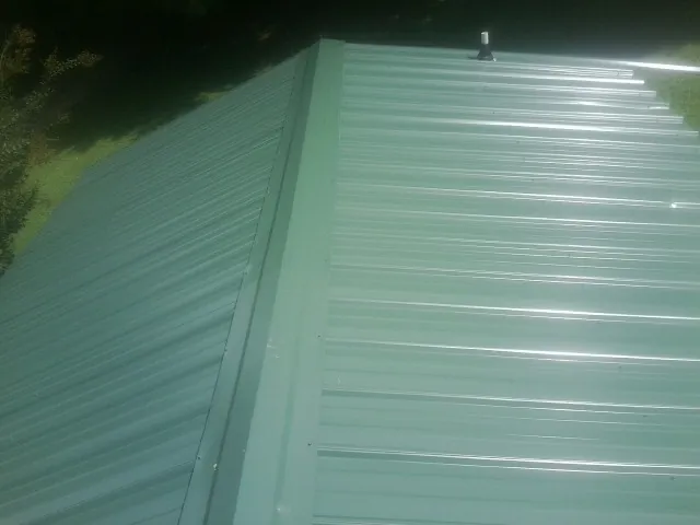 New green metal panels meeting at the ridge of a roof — Flat Roof Repair work by our crew in Eden Valley