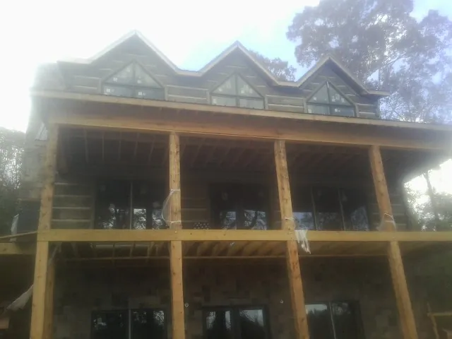 Dormers and porch framing on a large log home under construction — Roof Coating work by our crew in Eden Valley