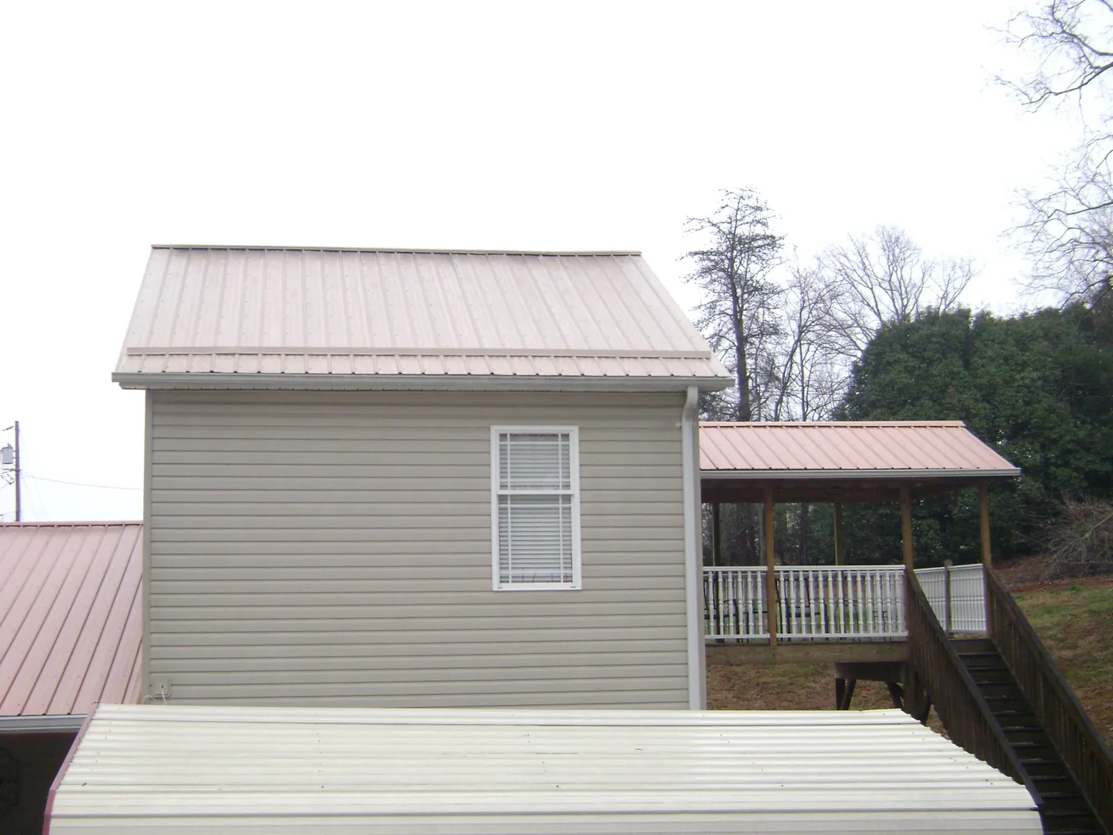 Tan metal roofs on a two story addition and attached porch, from a Roof Replacement job in Eden Valley
